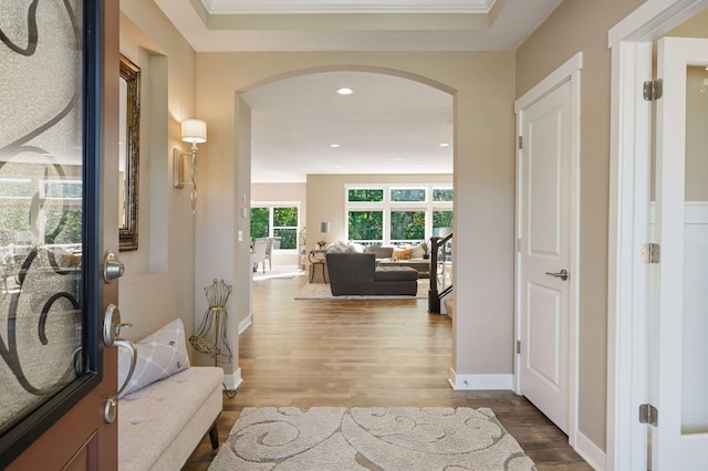hallway featuring baseboards, arched walkways, wood finished floors, and recessed lighting