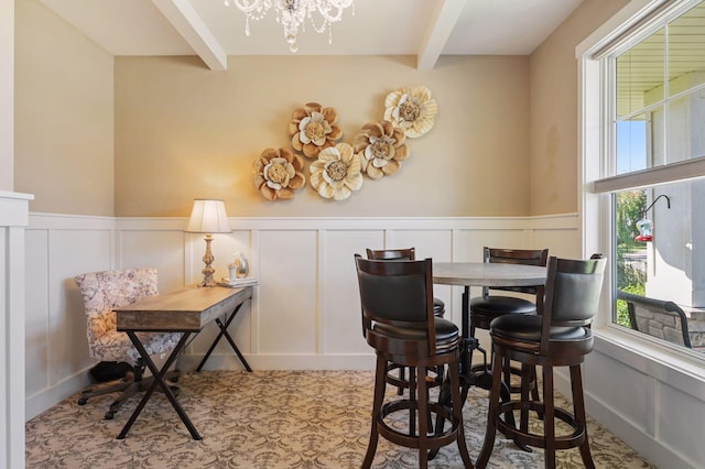 dining room with a wainscoted wall, beamed ceiling, a decorative wall, and a chandelier
