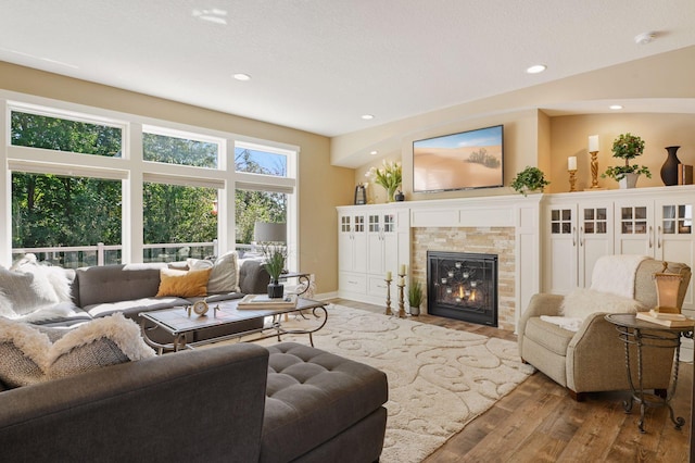 living area with a tiled fireplace, recessed lighting, baseboards, and wood finished floors
