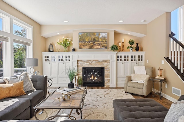 living area featuring visible vents, stairs, wood finished floors, baseboards, and a tiled fireplace