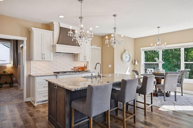kitchen featuring an inviting chandelier, a sink, white cabinetry, and custom exhaust hood