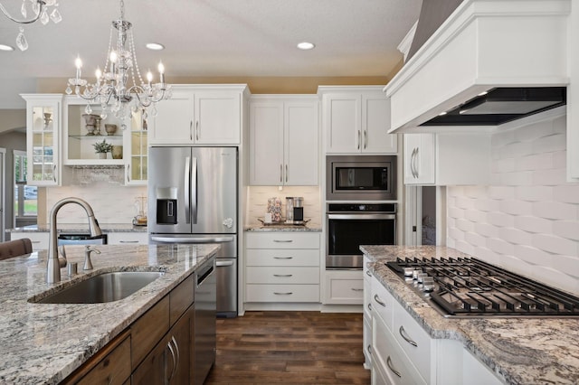 kitchen with stainless steel appliances, decorative backsplash, a sink, and custom range hood