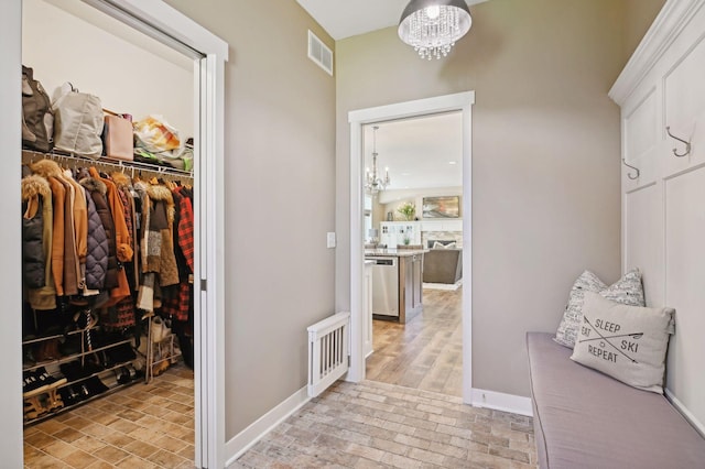 mudroom featuring visible vents, baseboards, brick floor, and a notable chandelier