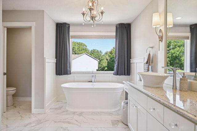 full bath featuring vanity, toilet, marble finish floor, a wainscoted wall, and a freestanding tub