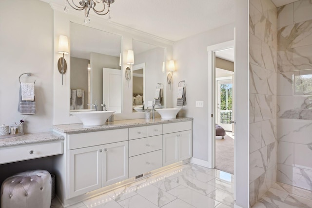 ensuite bathroom with double vanity, marble finish floor, baseboards, a sink, and ensuite bath