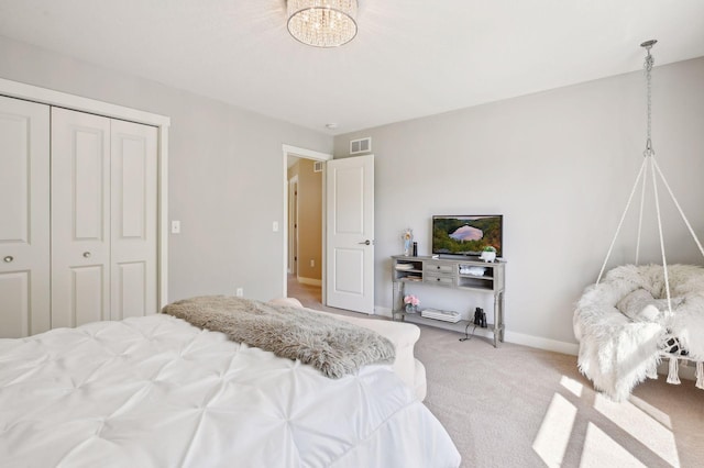 bedroom with visible vents, a closet, light carpet, baseboards, and a chandelier