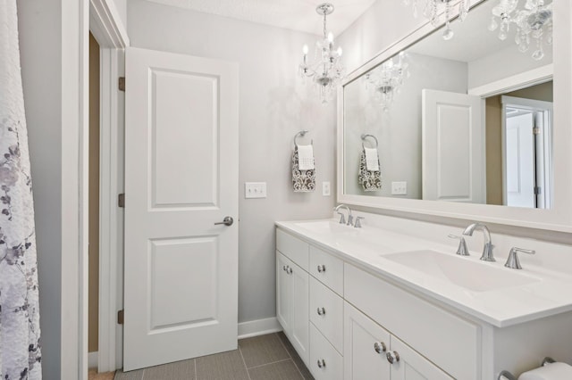 bathroom featuring a sink, baseboards, an inviting chandelier, and double vanity