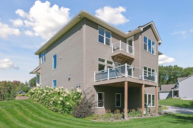 rear view of house featuring a yard and a balcony