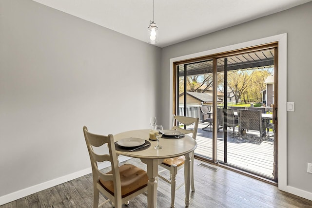 dining area with baseboards, visible vents, and wood finished floors
