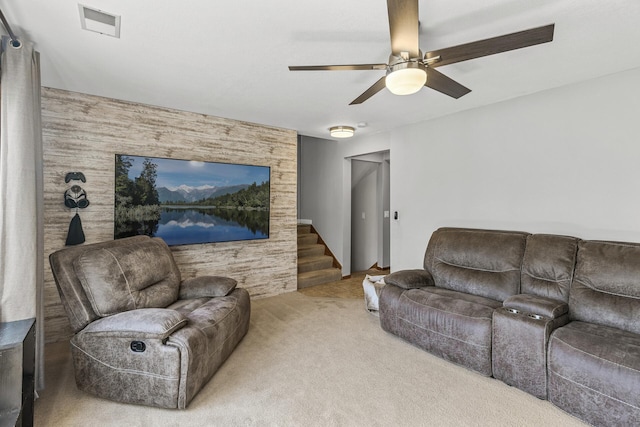 carpeted living area featuring stairway and ceiling fan