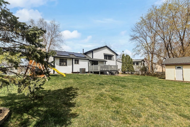 back of house featuring central AC unit, roof mounted solar panels, a yard, and a deck