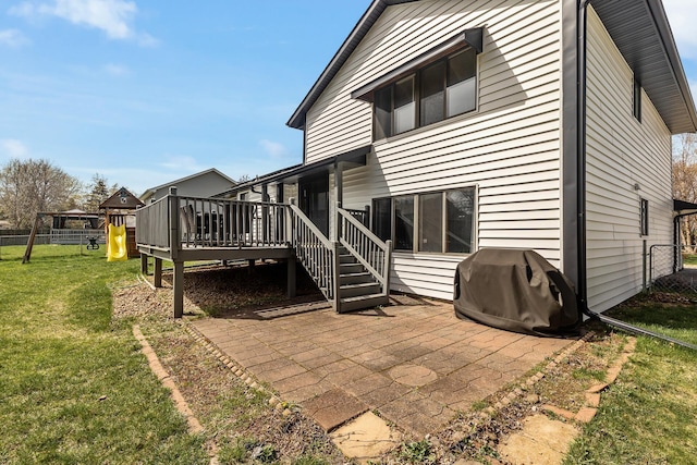 rear view of property with a wooden deck, fence, a playground, a patio area, and a lawn