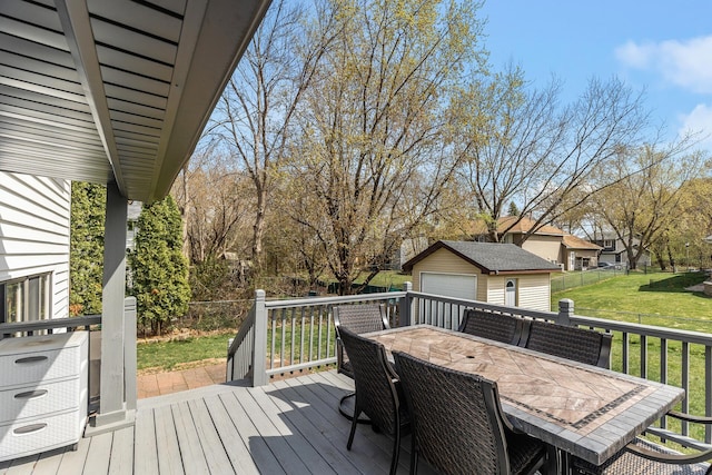 wooden deck featuring fence, outdoor dining area, a lawn, an outbuilding, and a detached garage