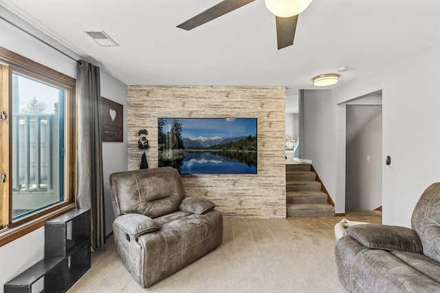carpeted living room featuring visible vents, a water view, stairway, and ceiling fan