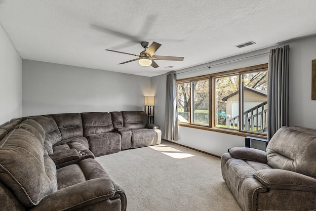 living area featuring a ceiling fan, a textured ceiling, visible vents, and carpet