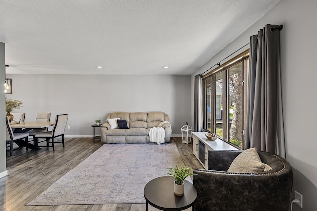 living room featuring baseboards, recessed lighting, a textured ceiling, and wood finished floors