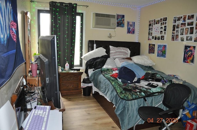 bedroom with wood finished floors and a wall mounted air conditioner