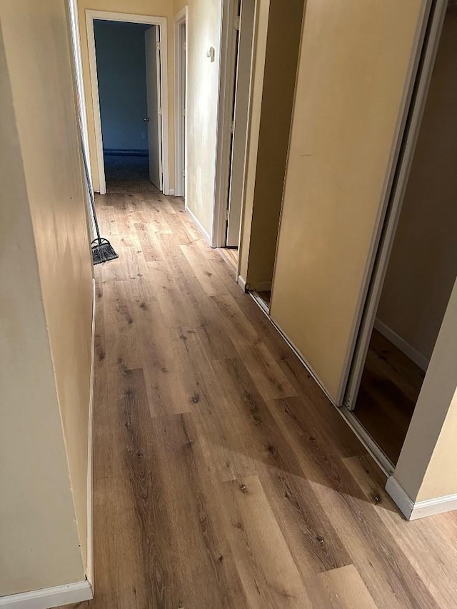 hall featuring light wood-style floors and baseboards