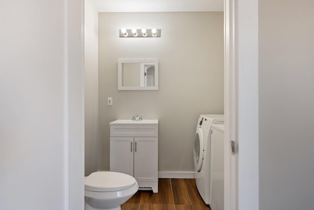 313 3rd St, Bovey, MN 55709 - bathroom featuring separate washer and dryer, vanity, wood finished floors, and toilet