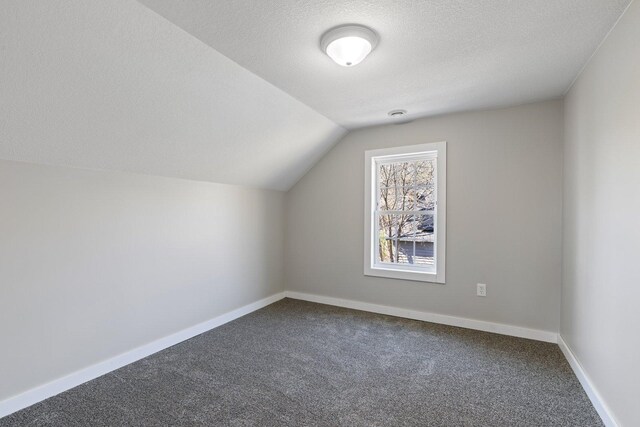 313 3rd St, Bovey, MN 55709 - additional living space featuring dark carpet, vaulted ceiling, a textured ceiling, and baseboards