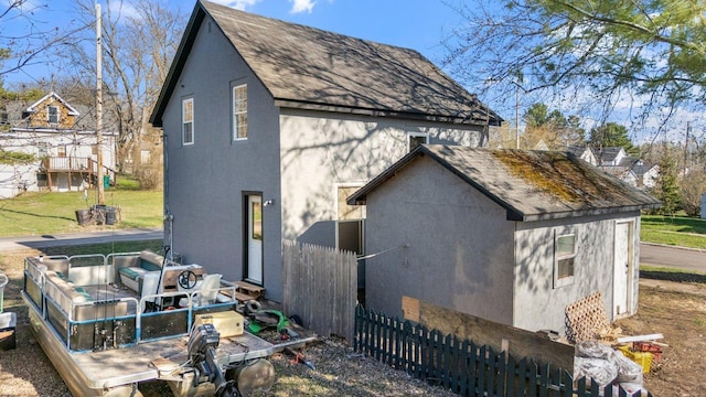 313 3rd St, Bovey, MN 55709 - back of house with stucco siding, roof with shingles, and fence