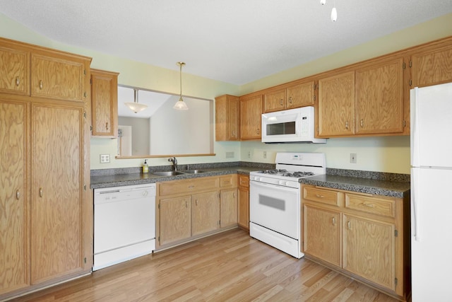 kitchen featuring dark countertops, a sink, white appliances, light wood-style flooring, and decorative light fixtures