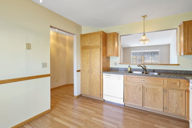 kitchen with light wood-type flooring, a sink, dishwasher, and dark countertops