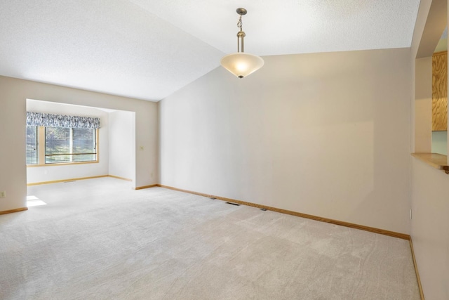 unfurnished room featuring baseboards, lofted ceiling, a textured ceiling, and light colored carpet