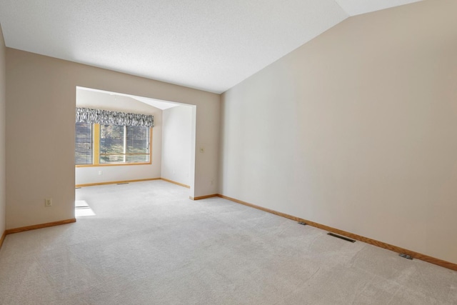 unfurnished room with baseboards, carpet flooring, lofted ceiling, and visible vents