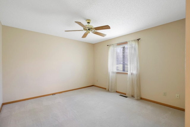 empty room with visible vents, a ceiling fan, baseboards, and light colored carpet