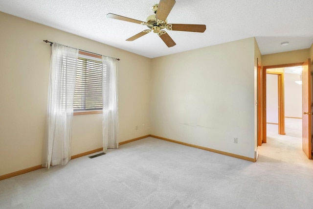 empty room with visible vents, baseboards, ceiling fan, light colored carpet, and a textured ceiling
