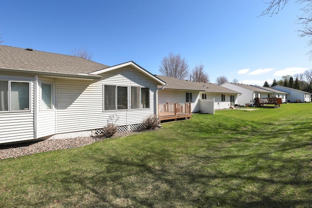 back of property featuring a yard, a wooden deck, and roof with shingles