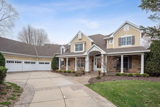view of front of home with covered porch, stone siding, a front yard, a shingled roof, and concrete driveway