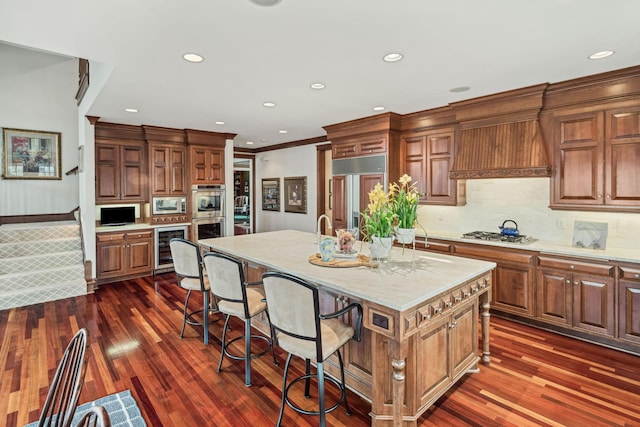 kitchen featuring beverage cooler, crown molding, built in appliances, and dark wood-style floors
