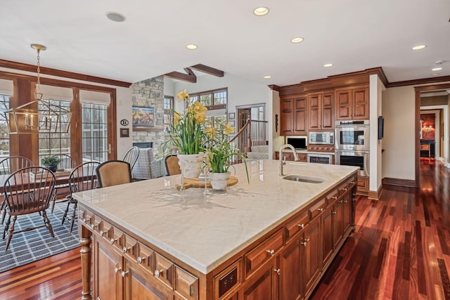 kitchen featuring a sink, stainless steel appliances, dark wood-style flooring, and a stone fireplace