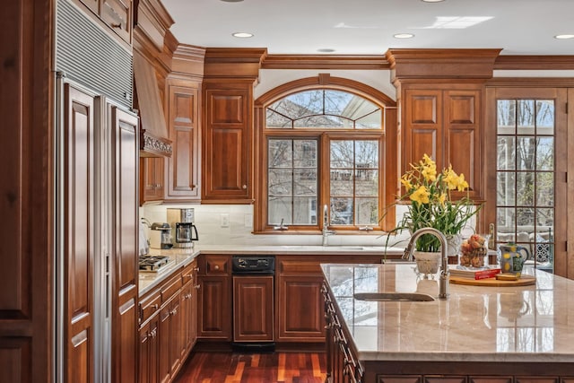 kitchen with light stone countertops, paneled built in refrigerator, and a sink