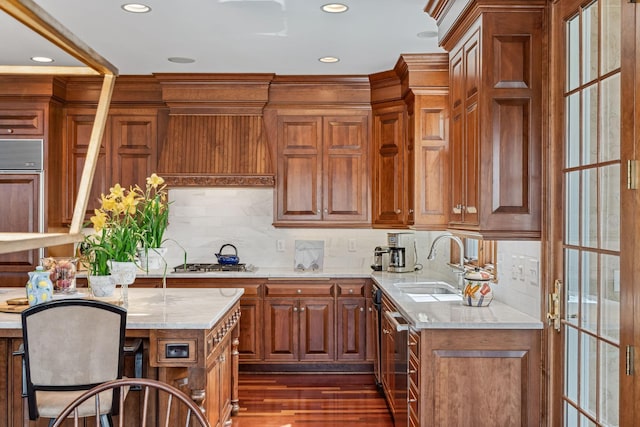 kitchen featuring brown cabinets, appliances with stainless steel finishes, light stone counters, a sink, and recessed lighting