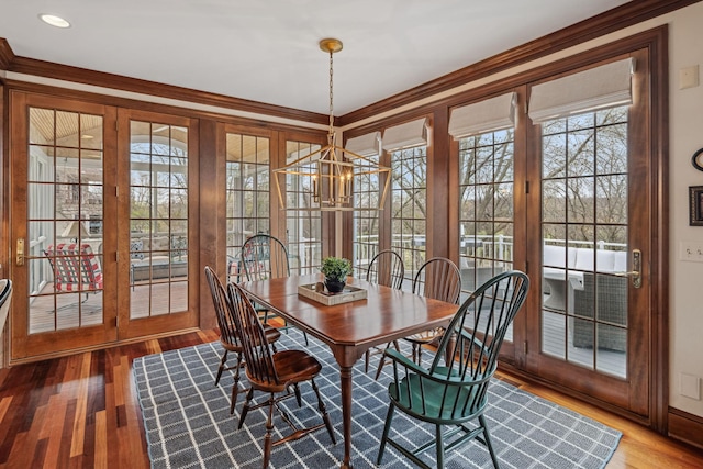 dining area featuring crown molding, baseboards, a chandelier, and wood finished floors