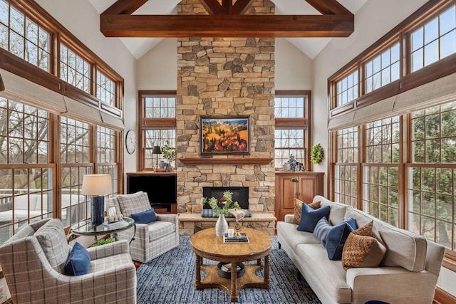 living room with a stone fireplace, a wealth of natural light, high vaulted ceiling, and beamed ceiling