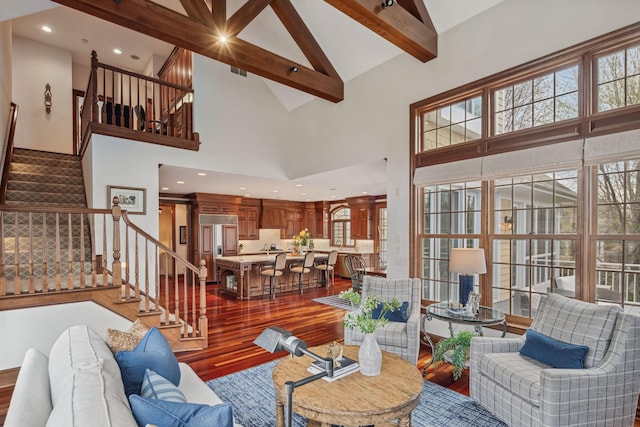 living room with beamed ceiling, wood finished floors, high vaulted ceiling, and stairway