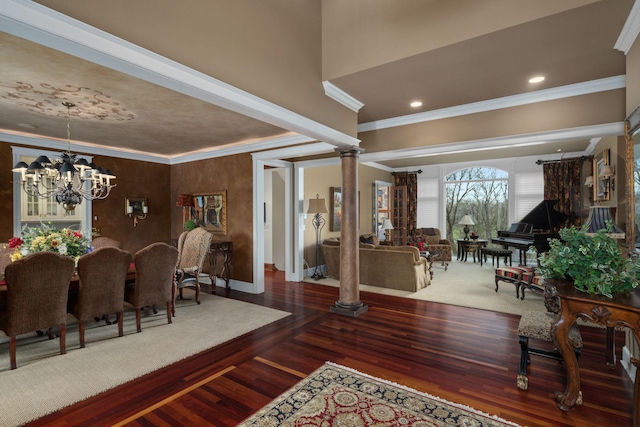 dining space featuring wood finished floors, baseboards, an inviting chandelier, ornamental molding, and ornate columns