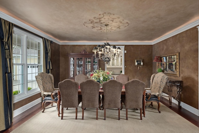 dining area with baseboards, crown molding, wood finished floors, and a chandelier