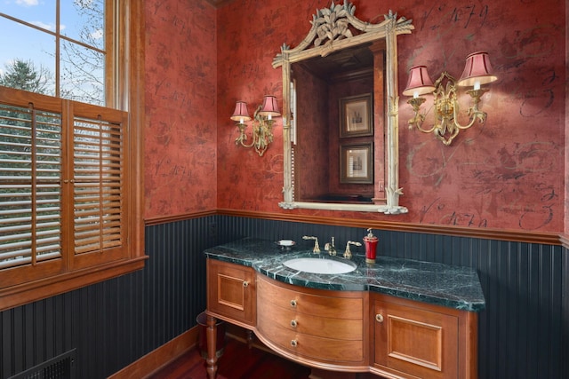 bathroom with vanity, a wainscoted wall, and wallpapered walls