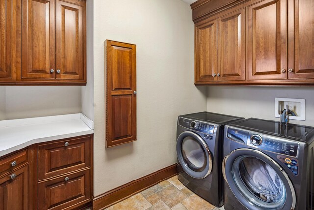 laundry room featuring baseboards, stone finish floor, independent washer and dryer, and cabinet space
