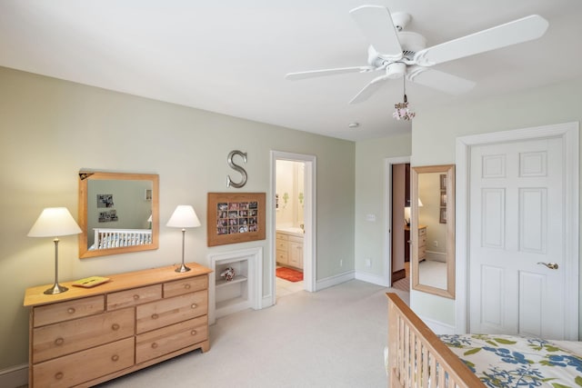 bedroom with baseboards, light carpet, a ceiling fan, and ensuite bath