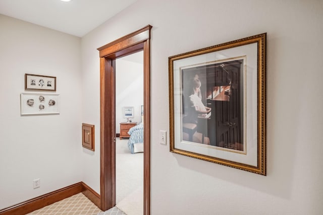 hallway featuring baseboards and carpet