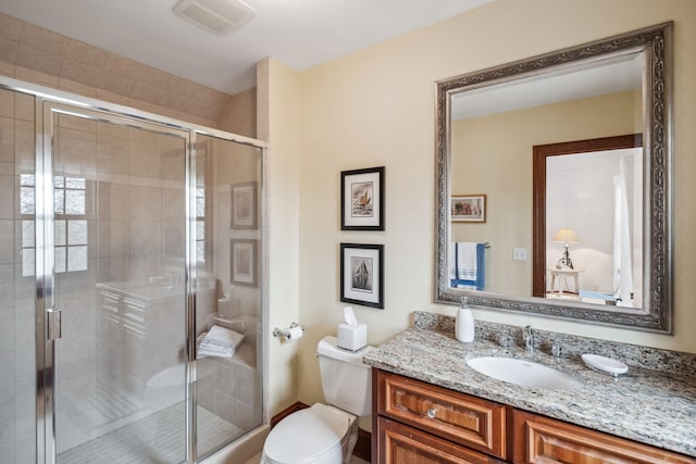bathroom with vanity, toilet, visible vents, and a stall shower
