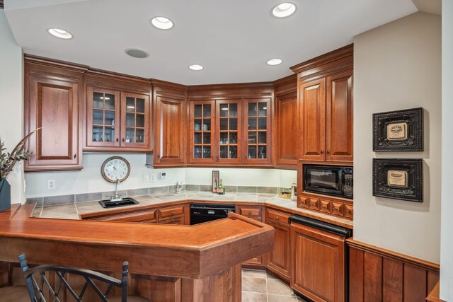 kitchen with a peninsula, glass insert cabinets, a breakfast bar area, recessed lighting, and black appliances