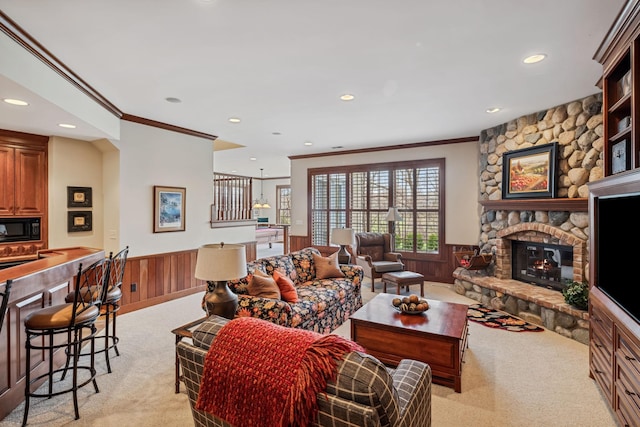 living room with light colored carpet, recessed lighting, crown molding, and a wainscoted wall