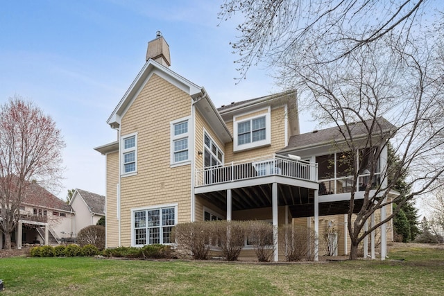 rear view of property featuring a sunroom, a wooden deck, a yard, and a chimney